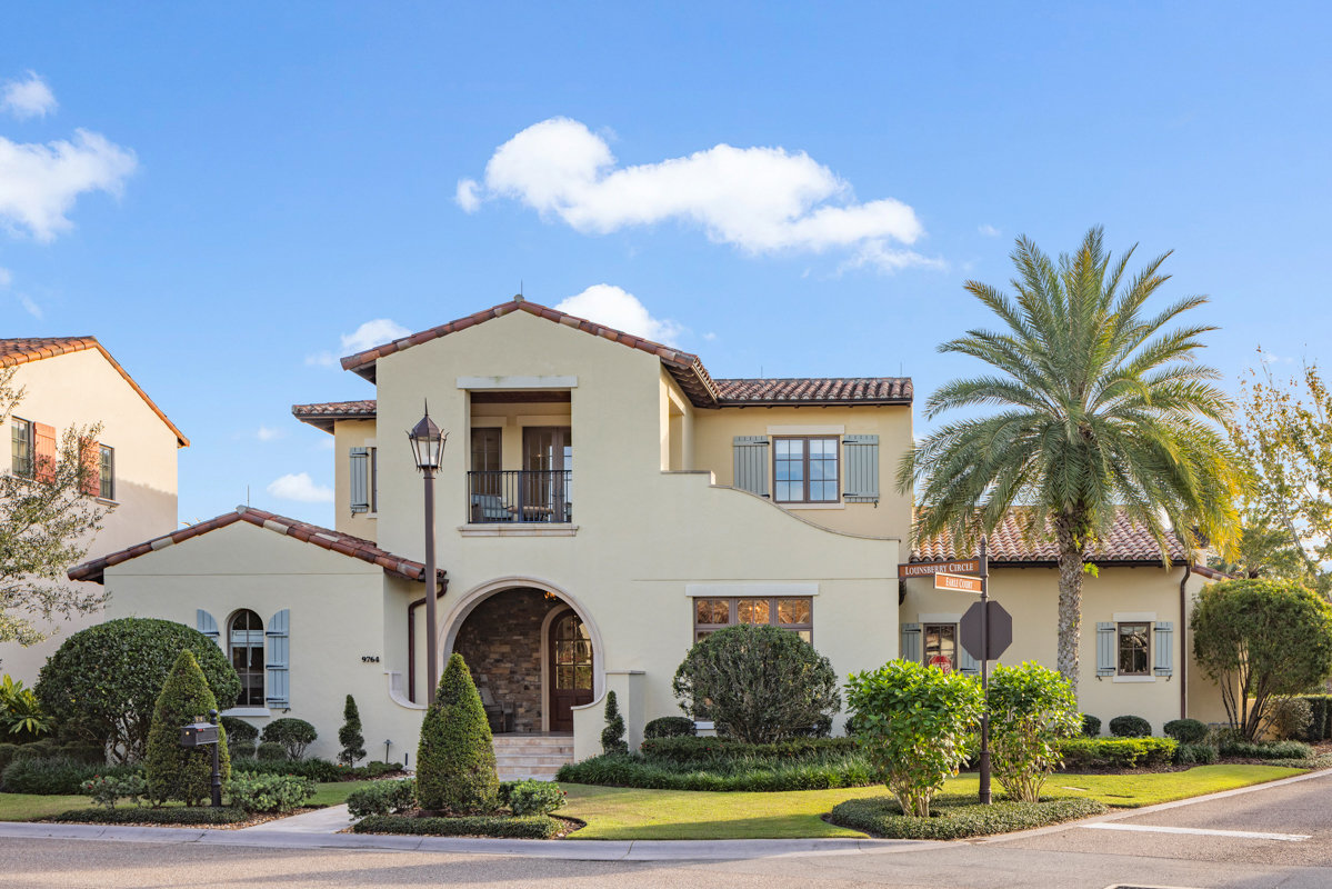 front of two story home with mediterranean design and lots of greenery